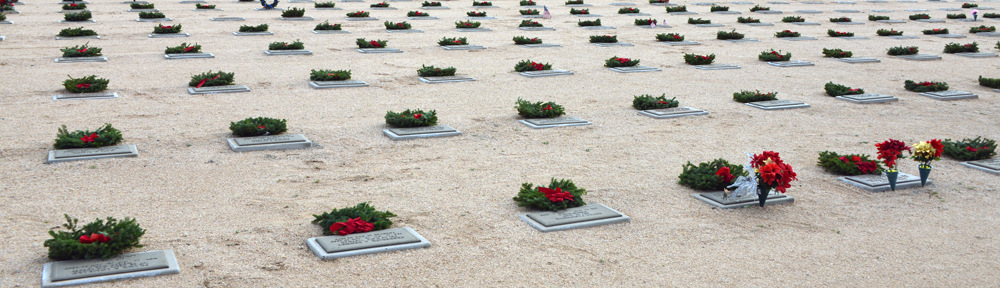 This photo shows Christmas wreaths on headstones at a National Cemetery.
